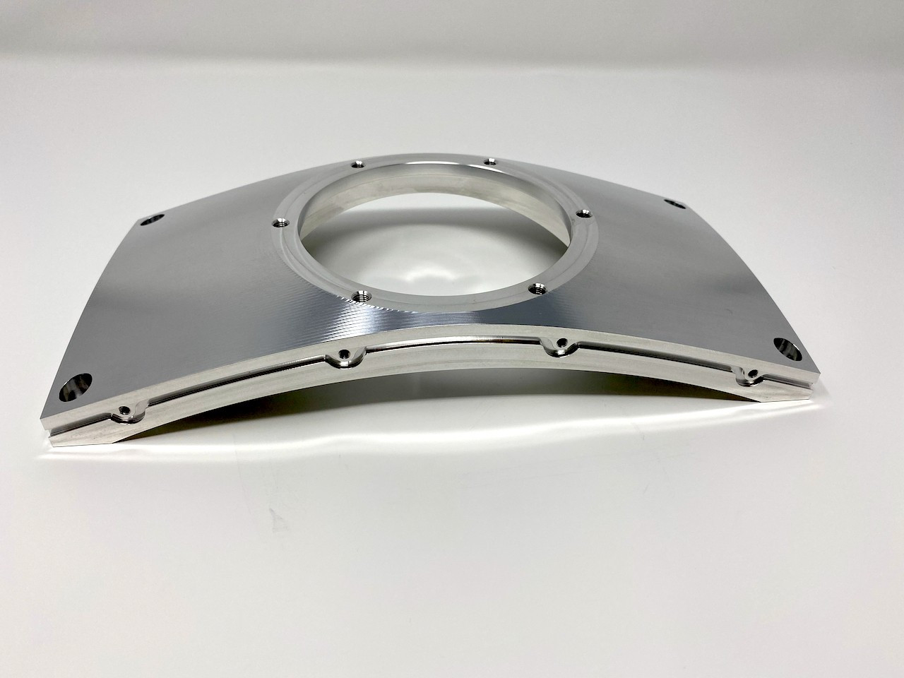Polished curved aluminum housing cover with a stepped central bore.