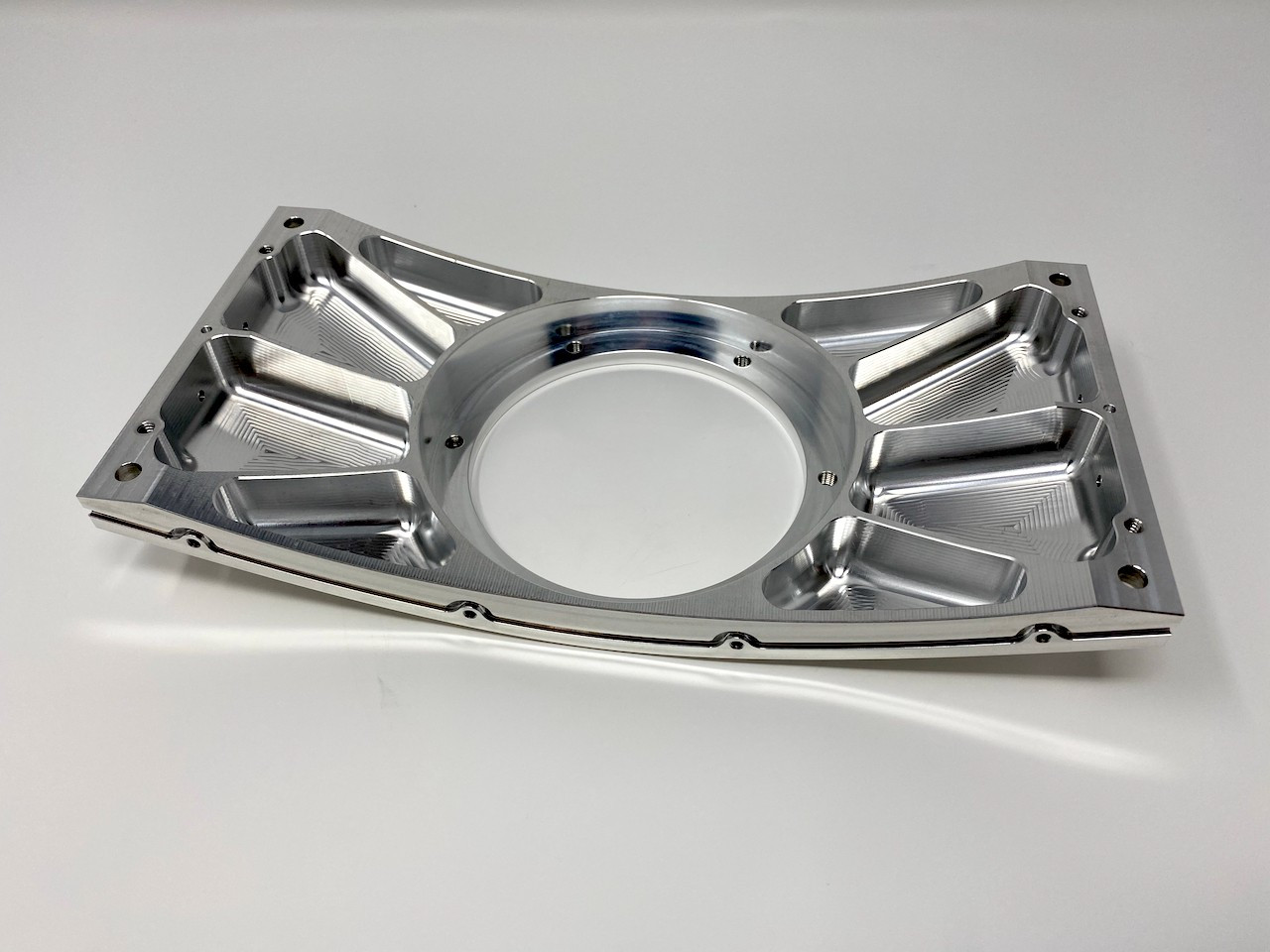Thin-wall ribbed aluminum structural bracket with a large central bore, machined from solid.