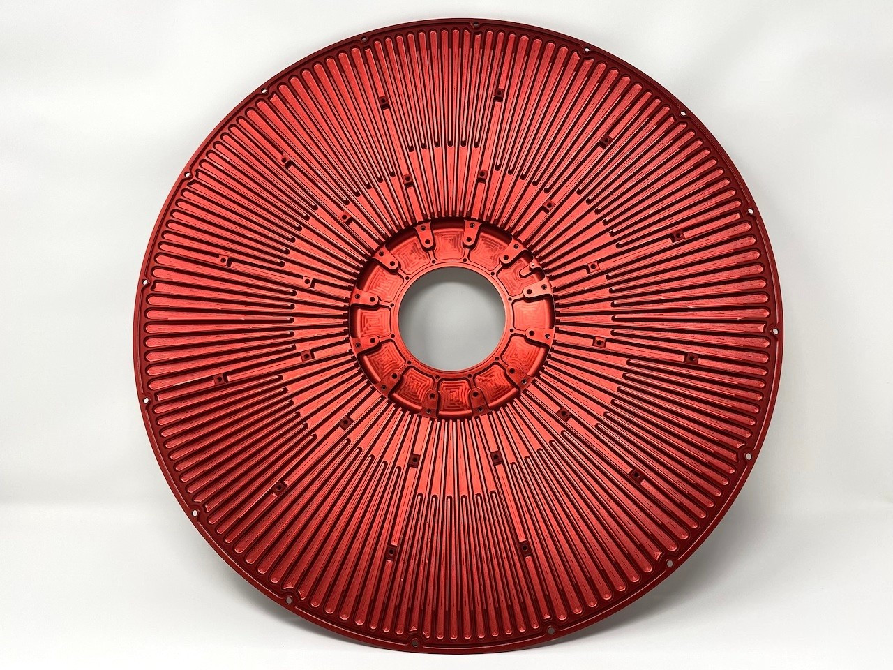 Red anodized machined aluminum rotor with a central hub and radial features.