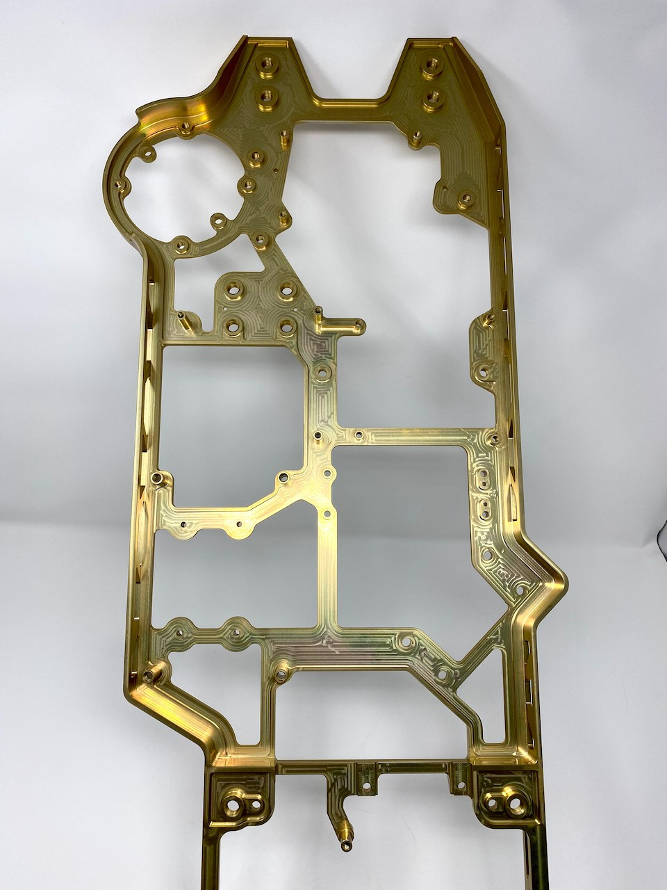 Tall gold-anodized machined frame with an open ladder structure and multiple bore features.