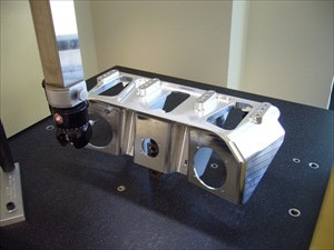 Machined part set up on a coordinate measuring machine with the probe head positioned over it.